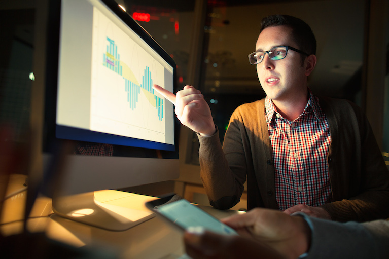 Coworker Discussing Findings On Screen At Night